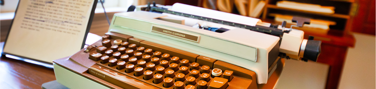 Angled view of Eudora Welty’s brown-and-white Smith-Corona electric typewriter with editing notes on a wooden desk at the Eudora Welty House & Garden.