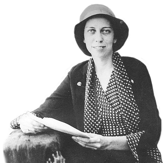Eudora Welty around age twenty in a cloche hat, geometric patterned blouse, and matching trimmed blazer, holding a letter in an envelope.