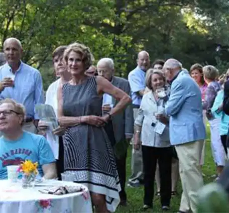 A group of seniors in semi-formal attire socializing on the Welty House lawn during an event.