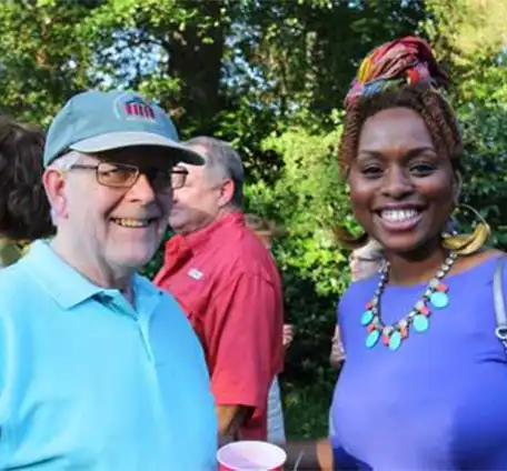 An African-American woman and a Caucasian man visit with one another during an informal event on the Welty House lawn.