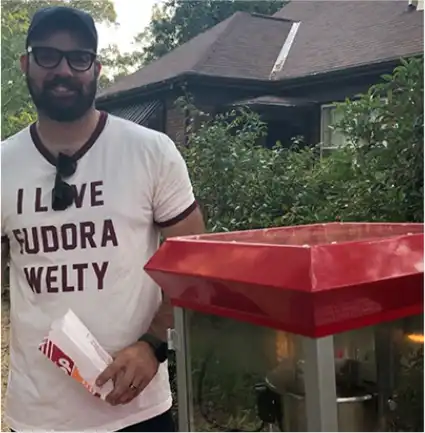 A volunteer serves popcorn in front of the Education and Visitors Center during an event at the Eudora Welty House & Garden.