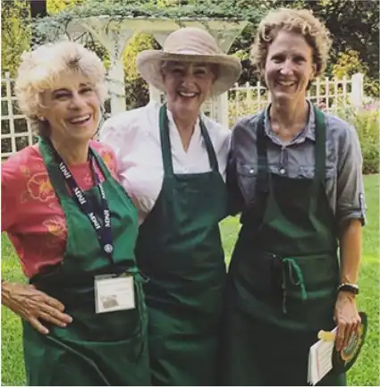 Three Cereus Weeder garden volunteers pose for a photo in their aprons after hosting a garden club at the Eudora Welty House & Garden.