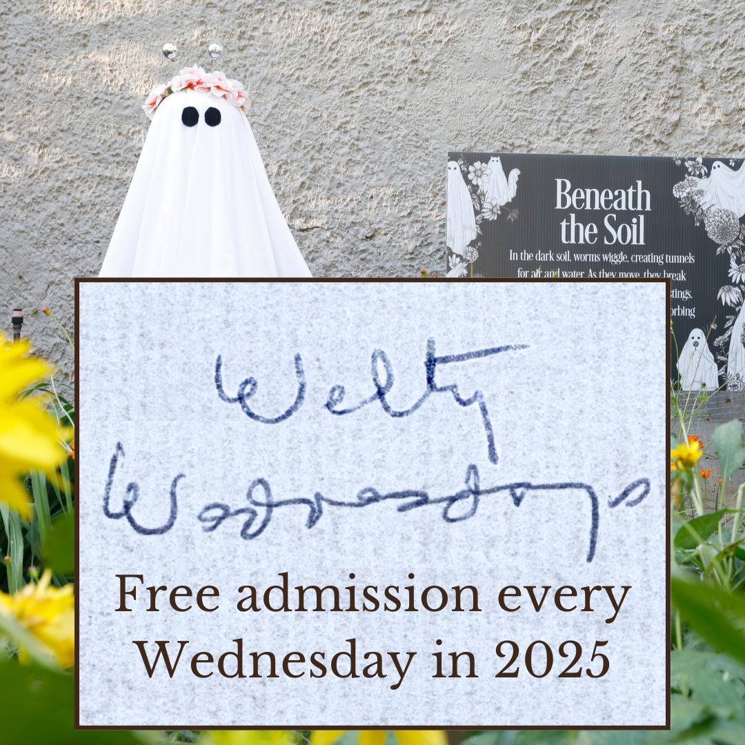 A ghost decoration with a flower crown stands in a garden beside a sign titled “Beneath the Soil.” In the foreground, a box overlay shows Eudora Welty’s handwriting with the words “Welty Wednesdays,” along with the text: “Free admission every Wednesday in 2025.”