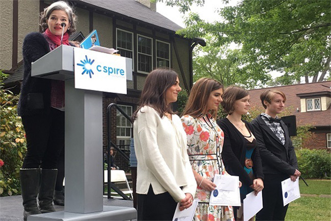 The Eudora Welty Foundation’s Sally Birdsall stands at a podium in front of the Welty House with four student nominees during the Scholastic Writing Awards ceremony.