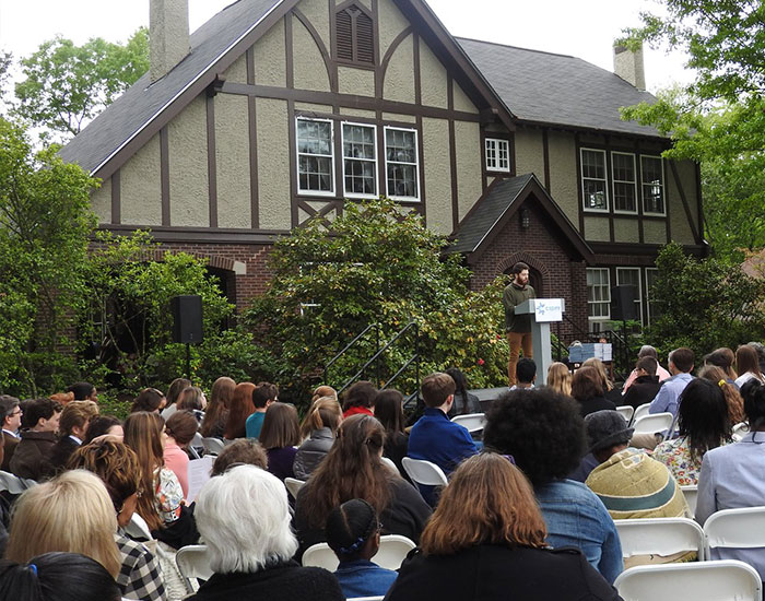 A speaker addresses a large crowd of guests on the Welty House lawn during the annual Scholastic Writing Awards ceremony.